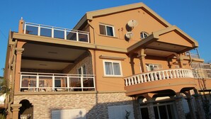Ein zweistöckiges Gebäude mit einem Balkon im oberen Geschoss und einer überdachten Fläche im Erdgeschoss.