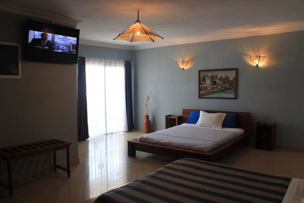 A bedroom with a bed, bedside tables, a TV, and a painting on the wall.