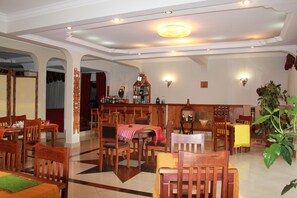 Un amplio comedor con mobiliario de madera, una barra con una variedad de botellas y una araña.