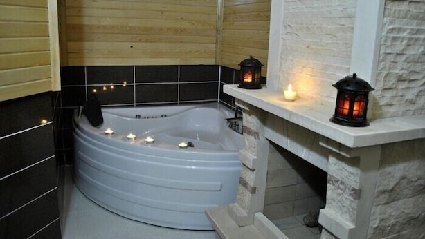 A modern bathroom with a freestanding bathtub, black and white tiles, and two lit candles on a shelf. - Assortie La Villa Hotel (Sile)