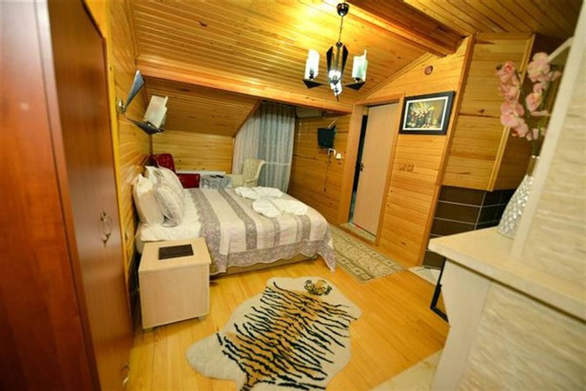 Habitación pequeña con cama, mesita de noche y alfombra estampada con motivos de animales.