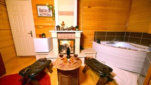 A room with a fireplace, a bathtub, and a small table with two chairs. - Assortie La Villa Hotel (Sile)