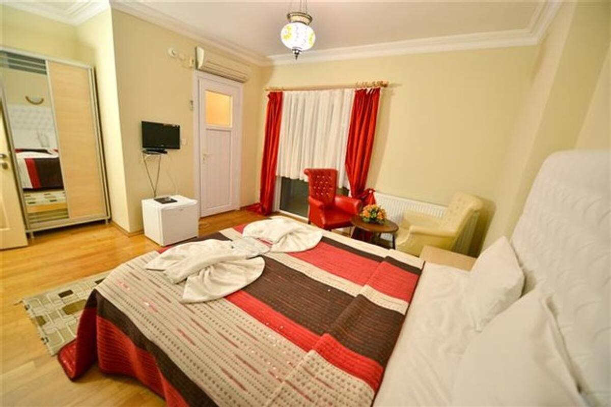 Una habitación de hotel con una cama, una silla, un escritorio, un televisor y un armario.
