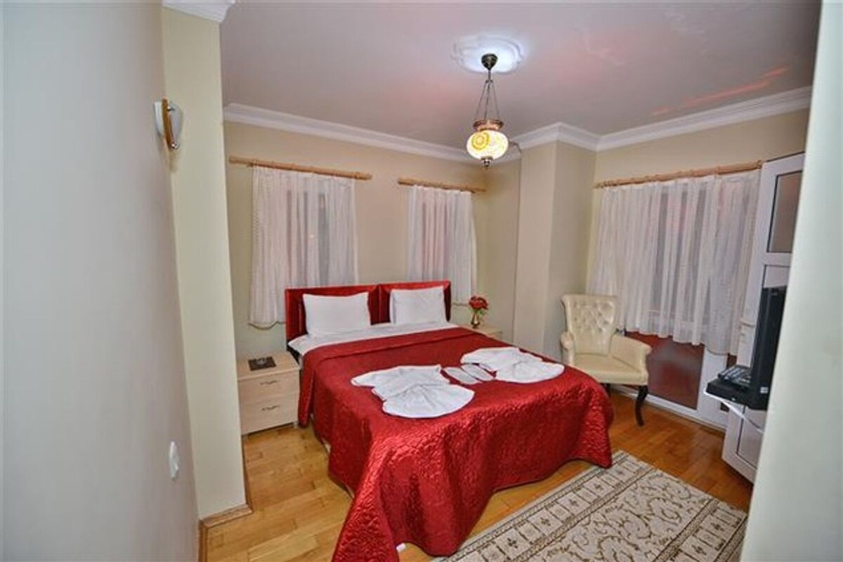 Ein Schlafzimmer mit zwei Betten, einem Sessel, einem Schreibtisch und einer Deckenleuchte.