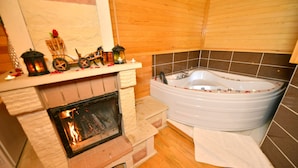 A bathroom with a bathtub, a fireplace, and wooden paneling. - Assortie La Villa Hotel (Sile)