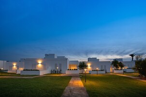 Un edificio moderno con un sendero central que conduce a una entrada protegida por una puerta.