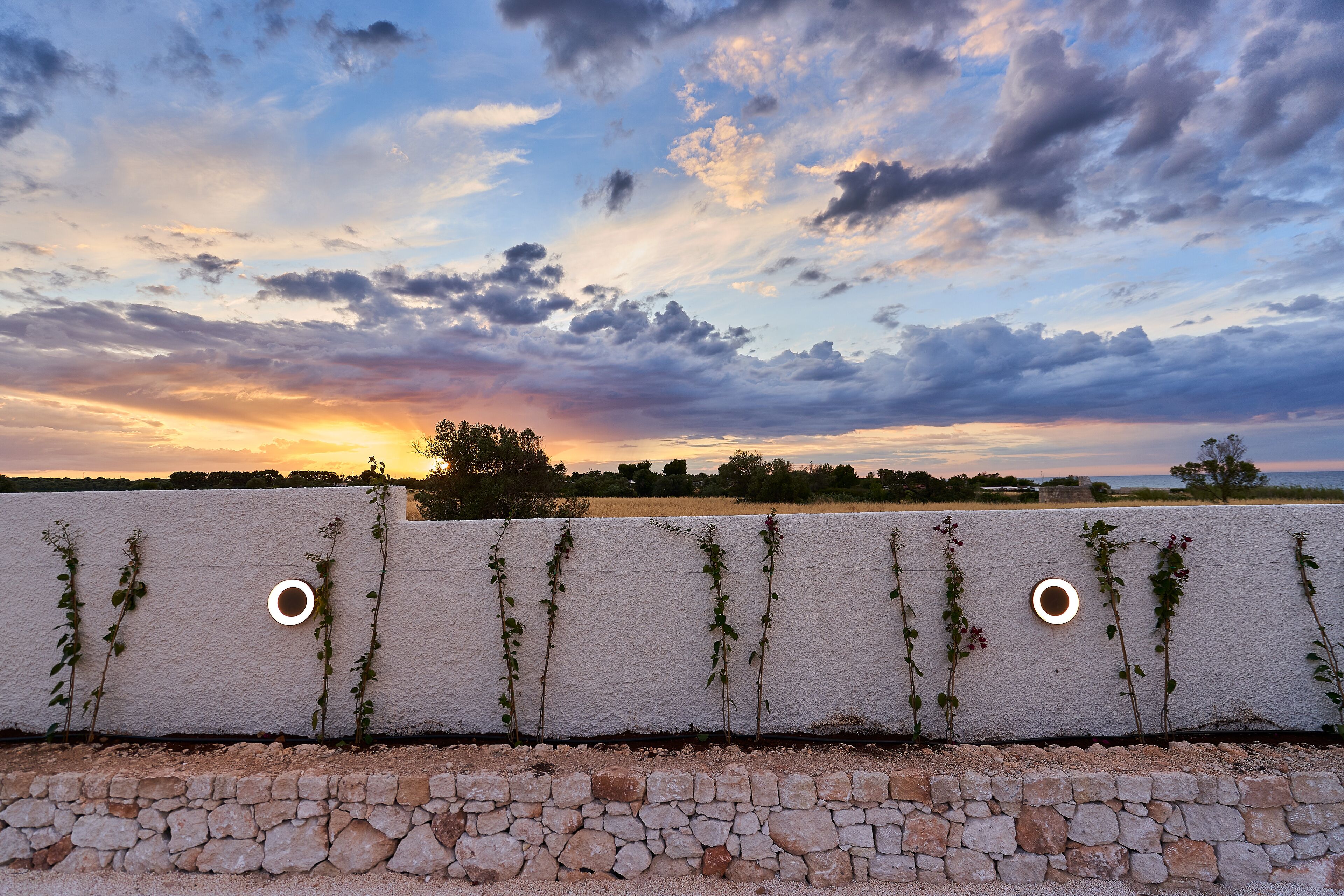 A stone wall with a textured white wall and two circular cutouts.