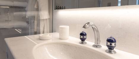 A modern bathroom with a white sink, two blue soap dispensers, a white soap dish, and a glass shower enclosure.
