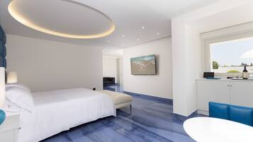 Een moderne hotelkamer met een bed, een bureau, een stoel, een eettafel, een raam en een schilderij aan de muur.
