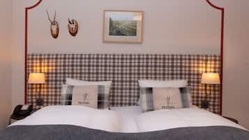 A hotel room with a plaid headboard, two bedside lamps, a framed picture, and two pillows with the name 'Malbun'.