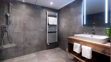 Une salle de bain moderne équipée d’une douche, d’un porte-serviettes, d’un lavabo et d’un miroir.