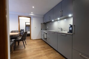 A modern kitchen with grey cabinets, a built-in oven, and a coffee machine.