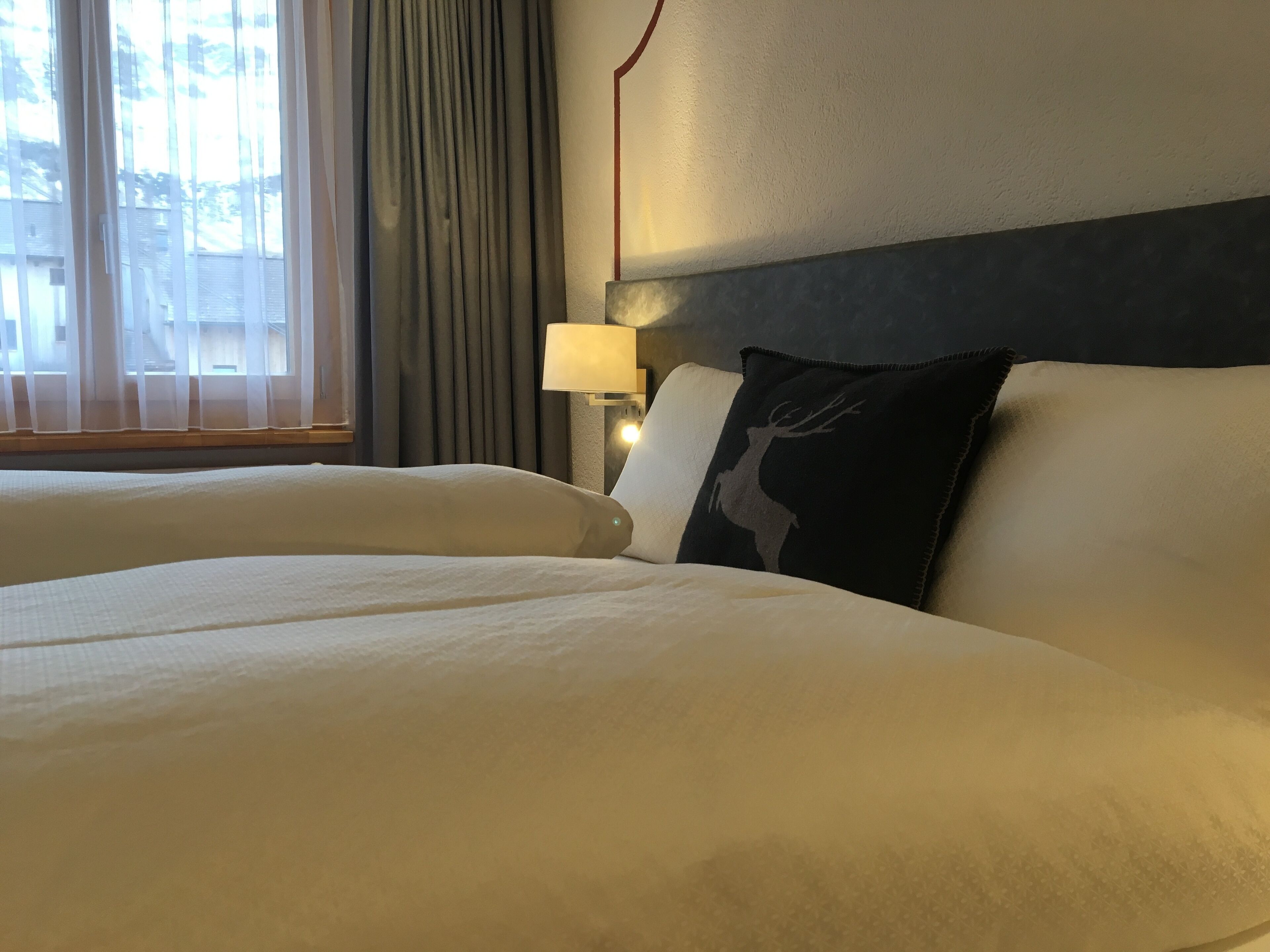 Ein Hotelzimmer mit zwei Betten, einer Lampe und einem Fenster mit Vorhängen.