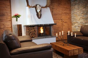 Una sala de estar acogedora con sofás de cuero, una chimenea con repisa de piedra y un cráneo de ciervo colgado.