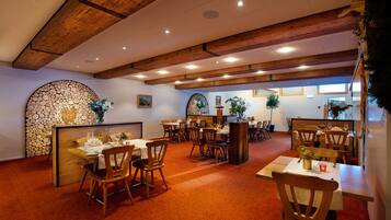 A restaurant with wooden beams, round tables, and chairs.