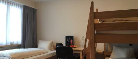 A room with two beds, a desk, and a chair.