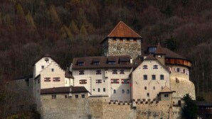 Ein schlösserartiges Gebäude mit mehreren Ebenen, Steinmauern und einem markanten Turm.