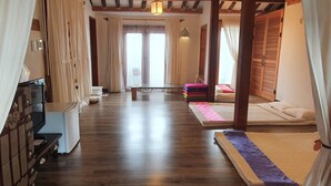A spacious room with wooden flooring, a bed with colorful bedding, a small table, and a bench. - Jeonju Greem (Jeonju)