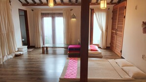 A room with a wooden floor, a bed with pillows, a bench, and a window with curtains. - Jeonju Greem (Jeonju)