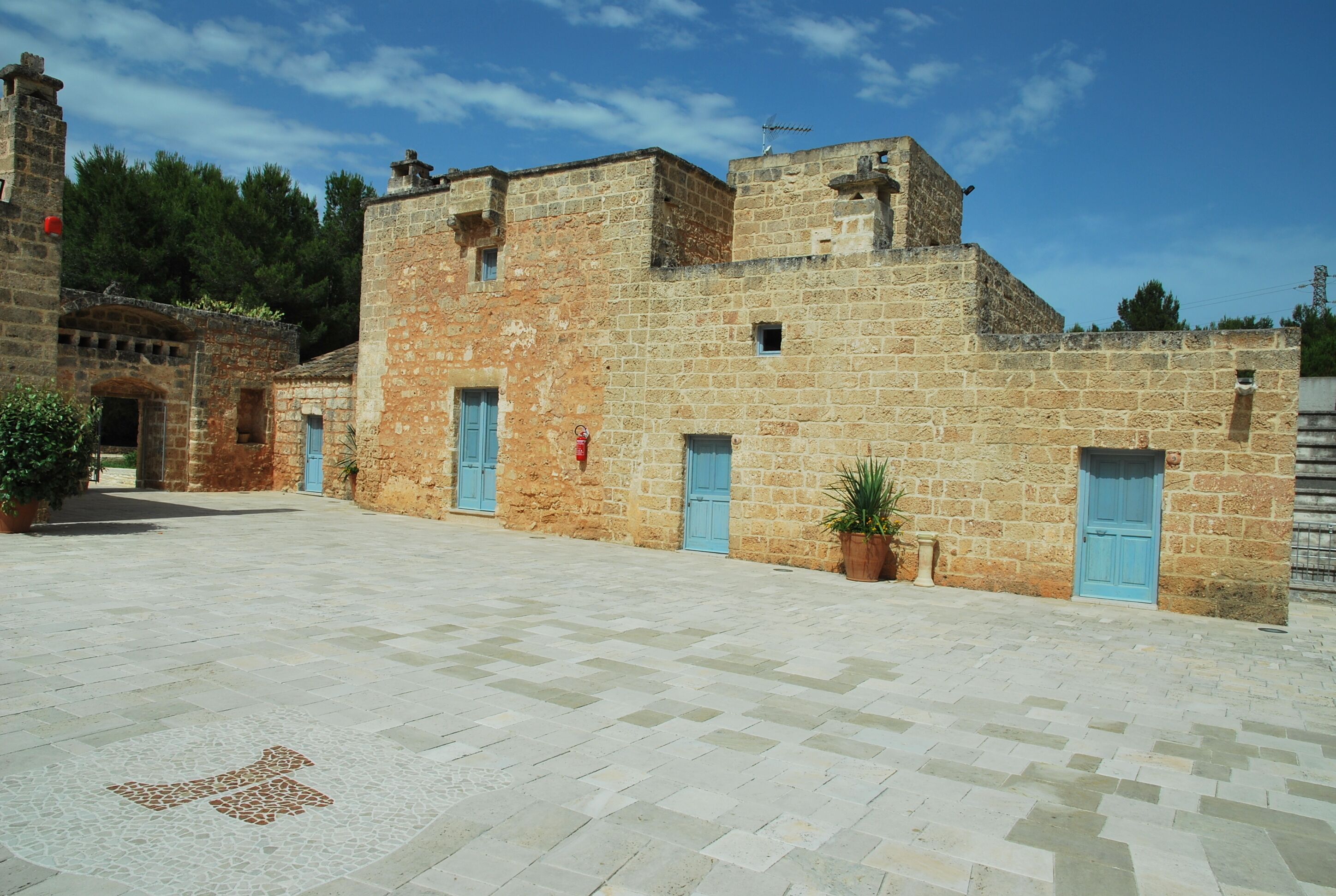 A courtyard with stone buildings, blue doors, and potted plants.