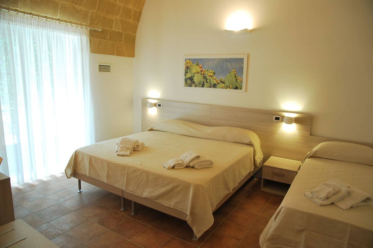 Une chambre d’hôtel avec deux lits, un tableau au mur et une fenêtre avec des rideaux.