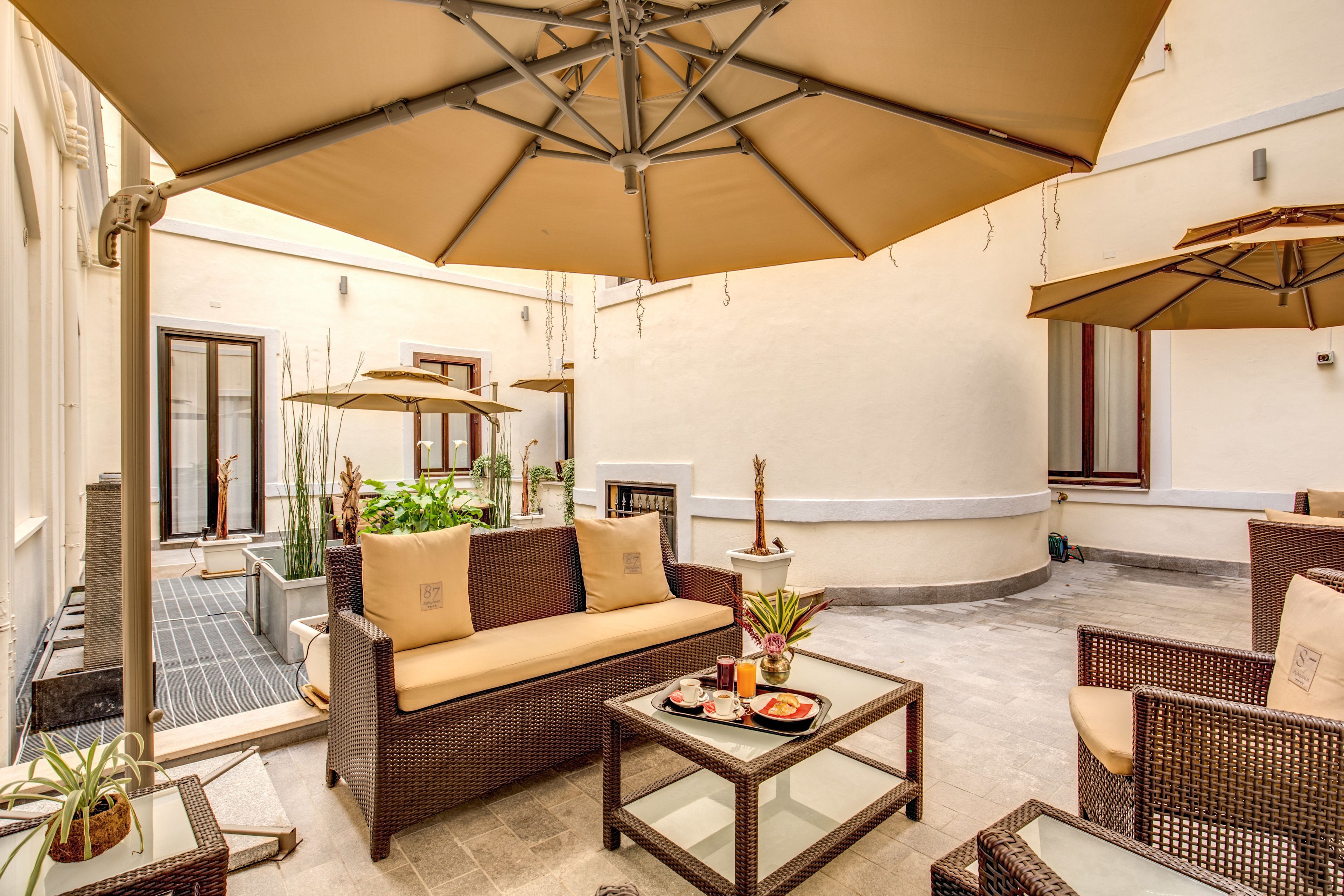 A sunlit outdoor seating area with wicker furniture, a sofa, and a table with a tray of food.