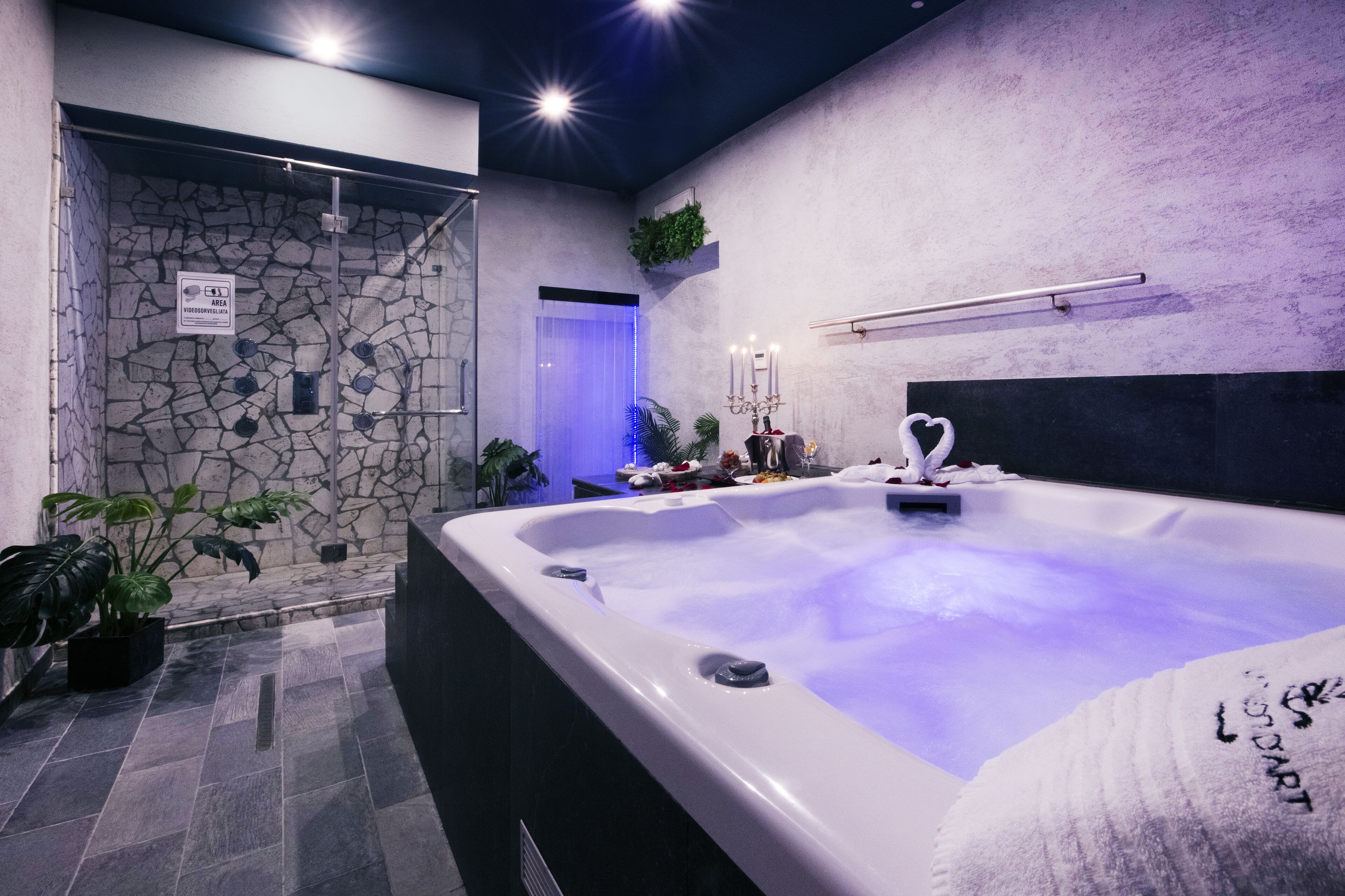 A spa area with a hot tub, stone walls, and potted plants.
