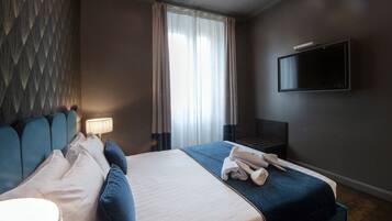 Una camera d'albergo con un letto grande, una televisione a parete e una finestra con tende.