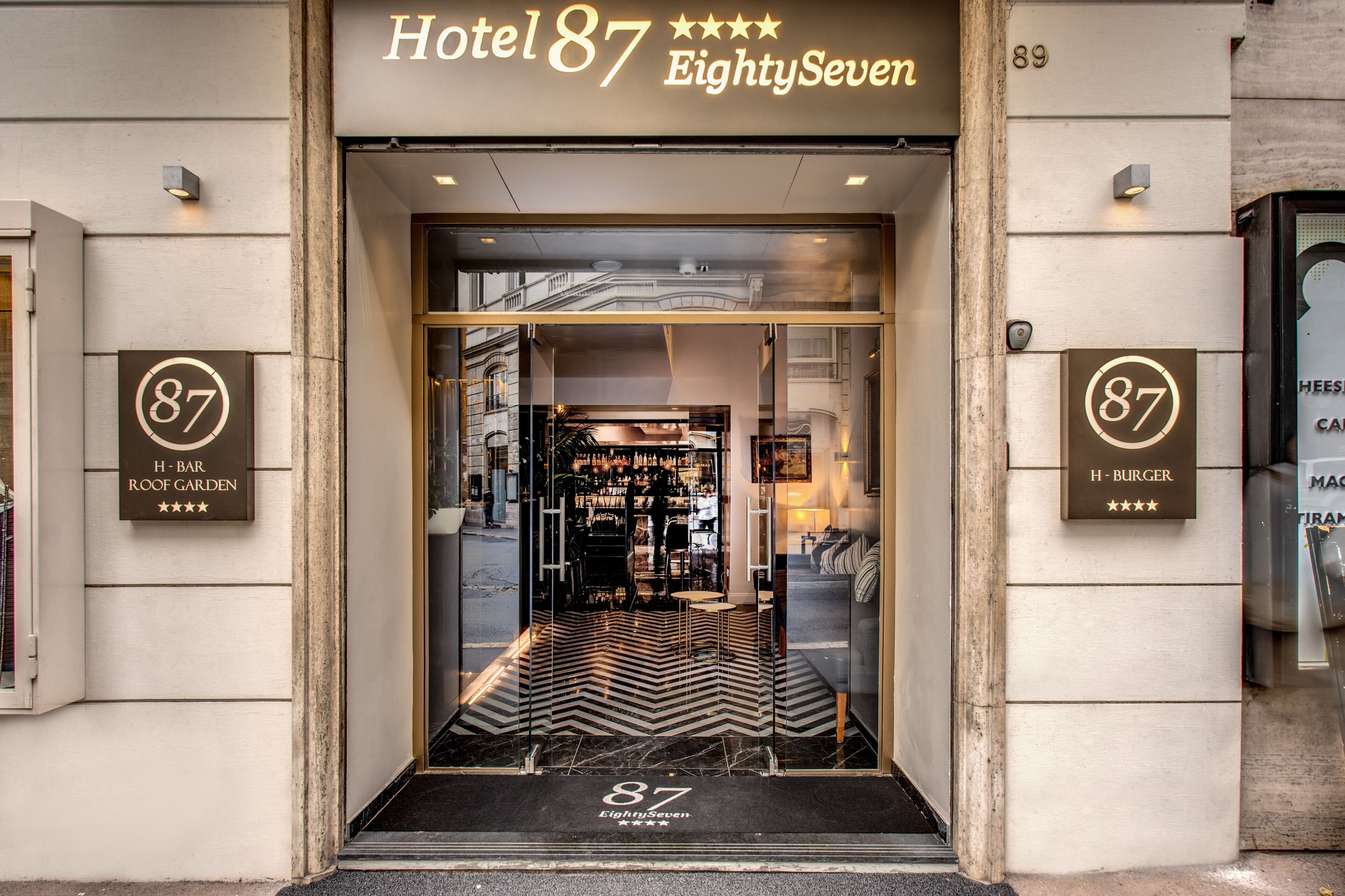 Hotel 87 EightySeven entrance with a modern design, including a bar and restaurant sign, and a clear view of the interior.