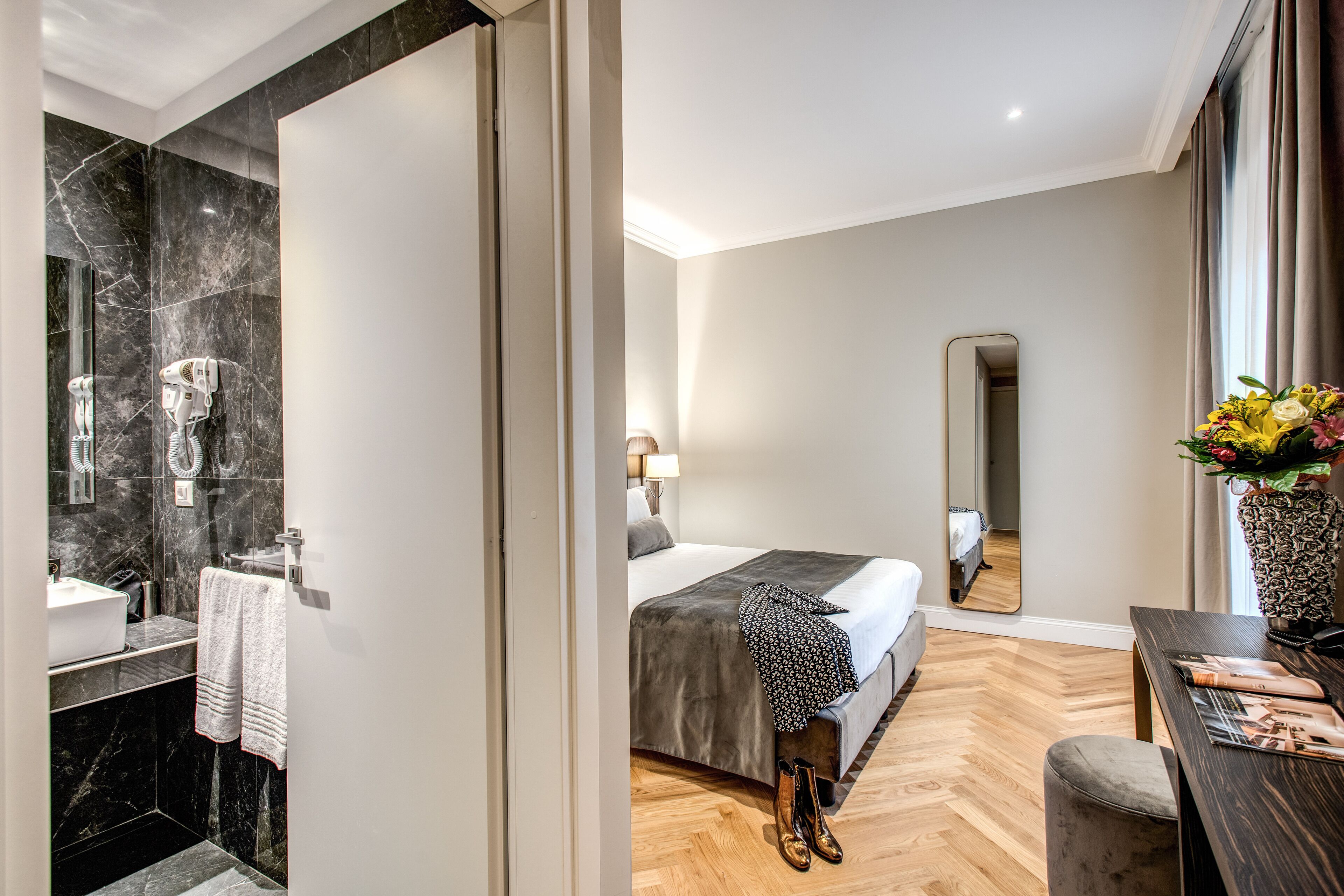 Ein Hotelzimmer mit Bad, Bett, Schreibtisch und Spiegel.
