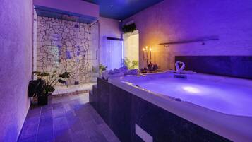 A modern bathroom with a stone wall, a large bathtub, and a vanity area.