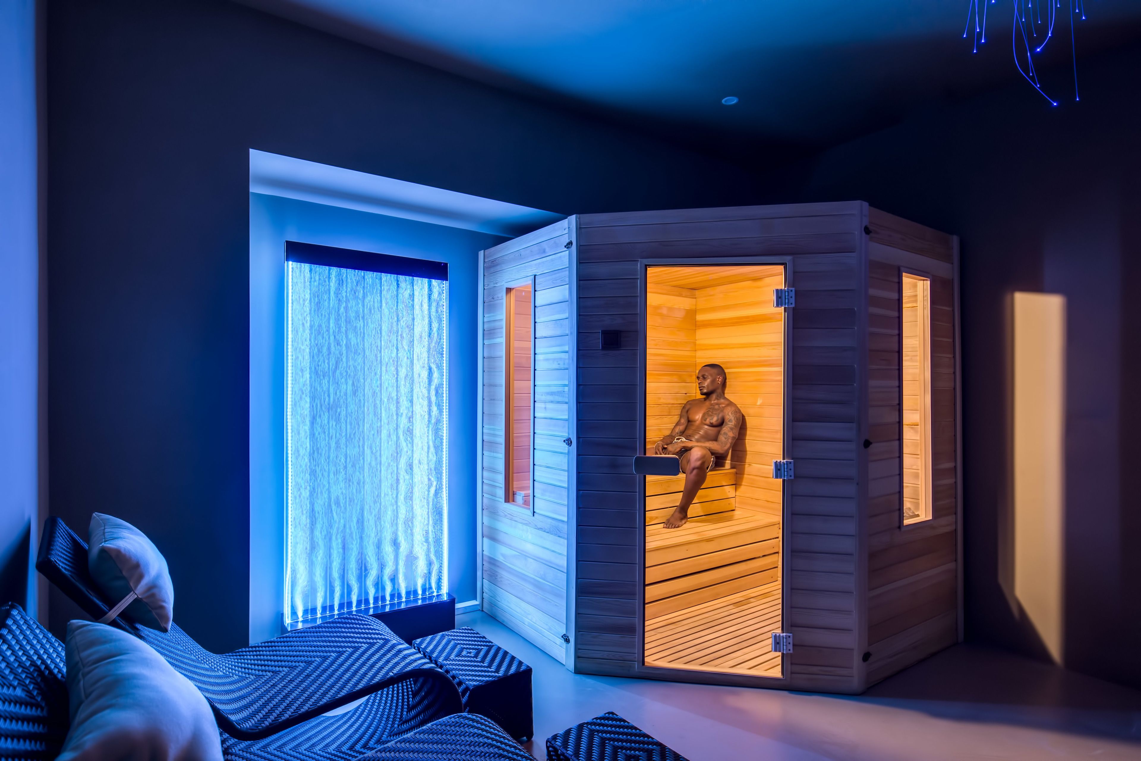 Une chambre moderne équipée d’un sauna, d’un canapé et d’une fenêtre avec des rideaux.