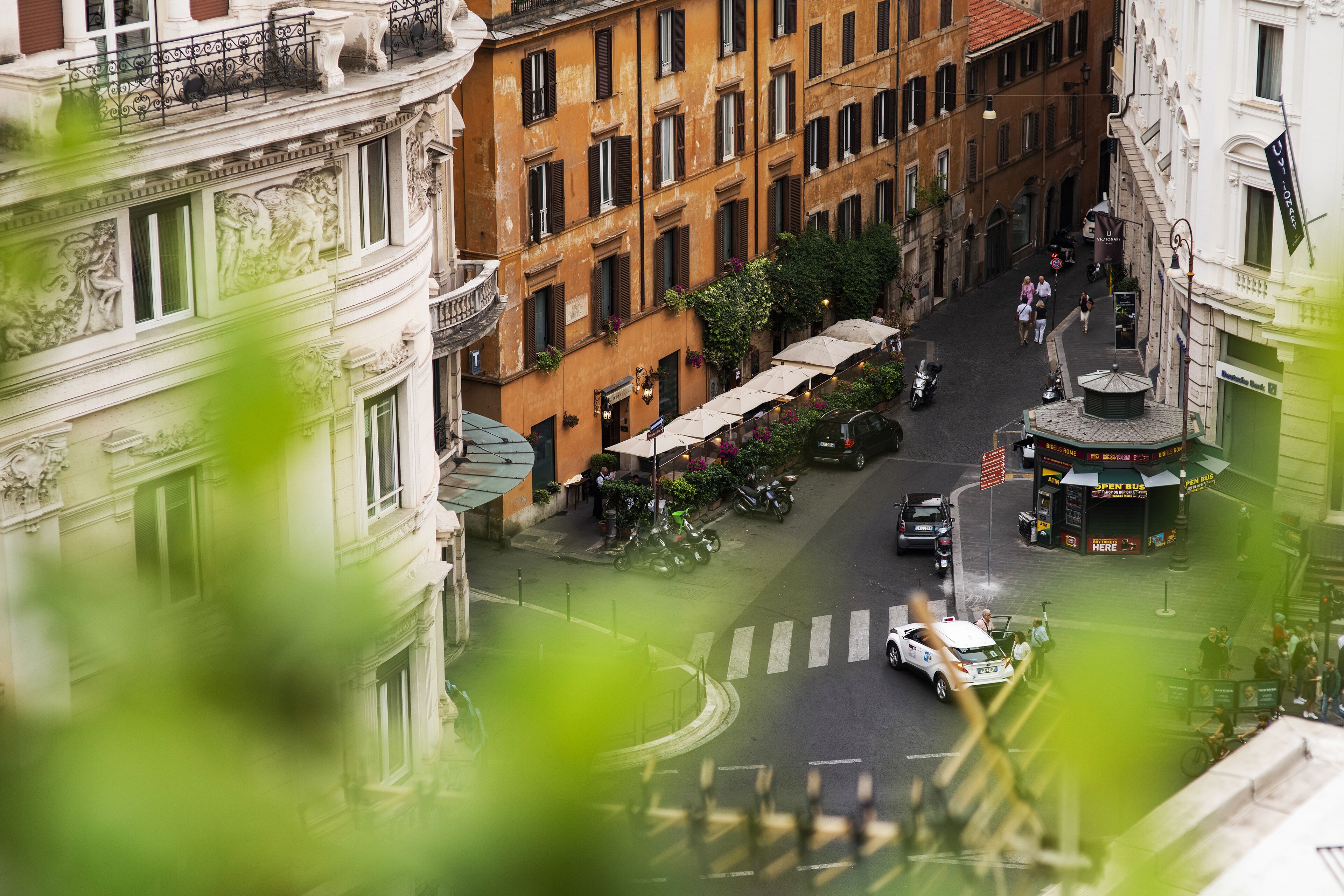 A street view with a roundabout, buildings with classical architecture, and a bus stop.