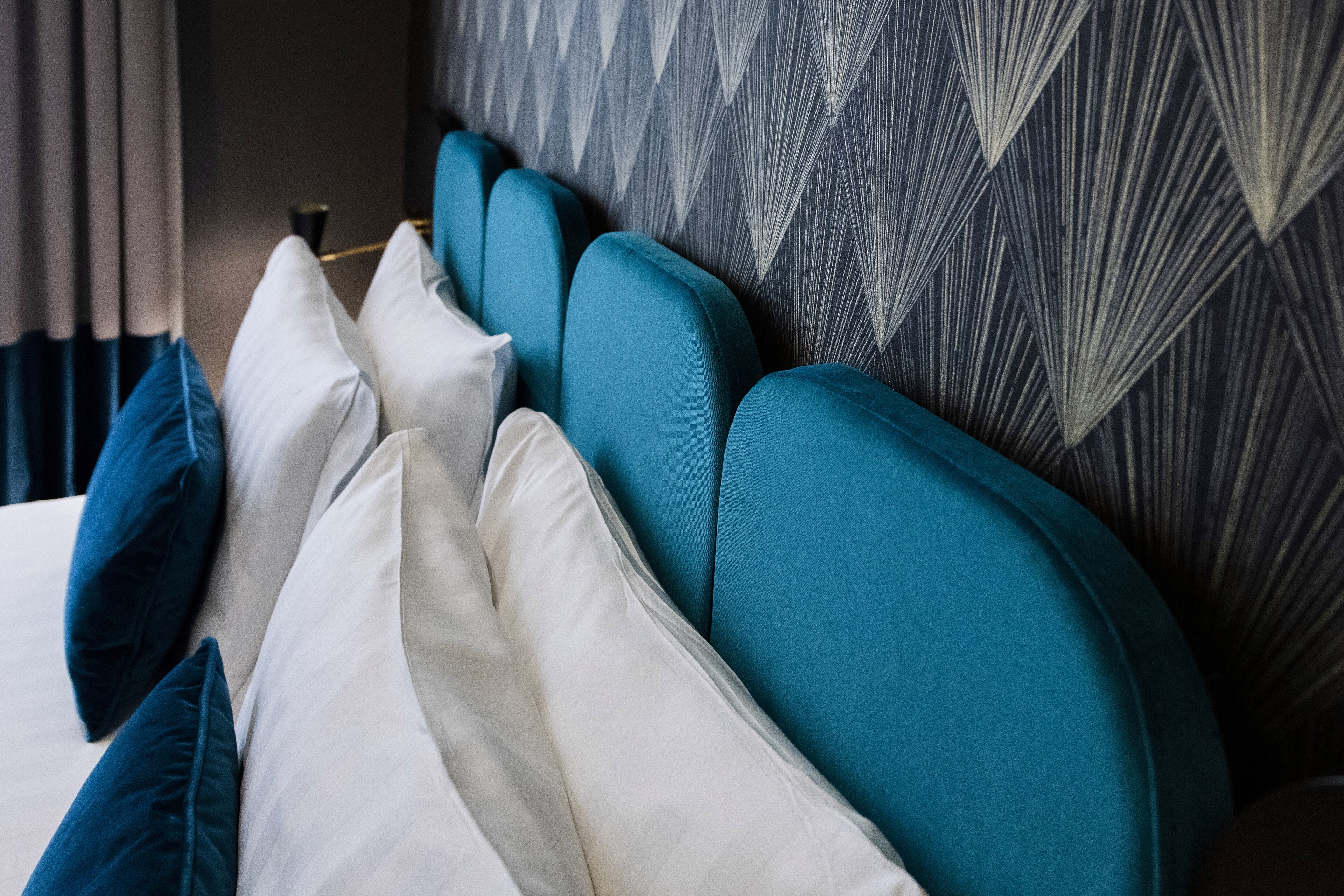 A bed with multiple pillows and a patterned headboard.