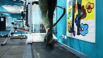 A treadmill in a gym with a blue wall and colorful flower artwork.