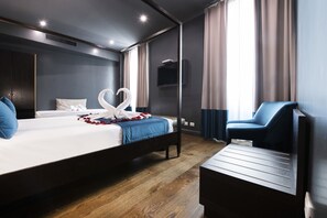 Ein Hotelzimmer mit einem großen Bett, einem Fernseher, einer Sitzecke und einem Fenster mit Vorhängen.