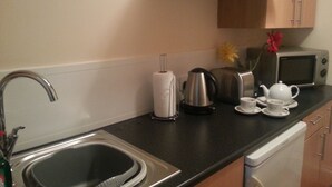 A kitchen with a sink, a toaster, a kettle, a microwave, and a tea set. - Bed and Blueberry, Two Bedroom Suite (Douglas)