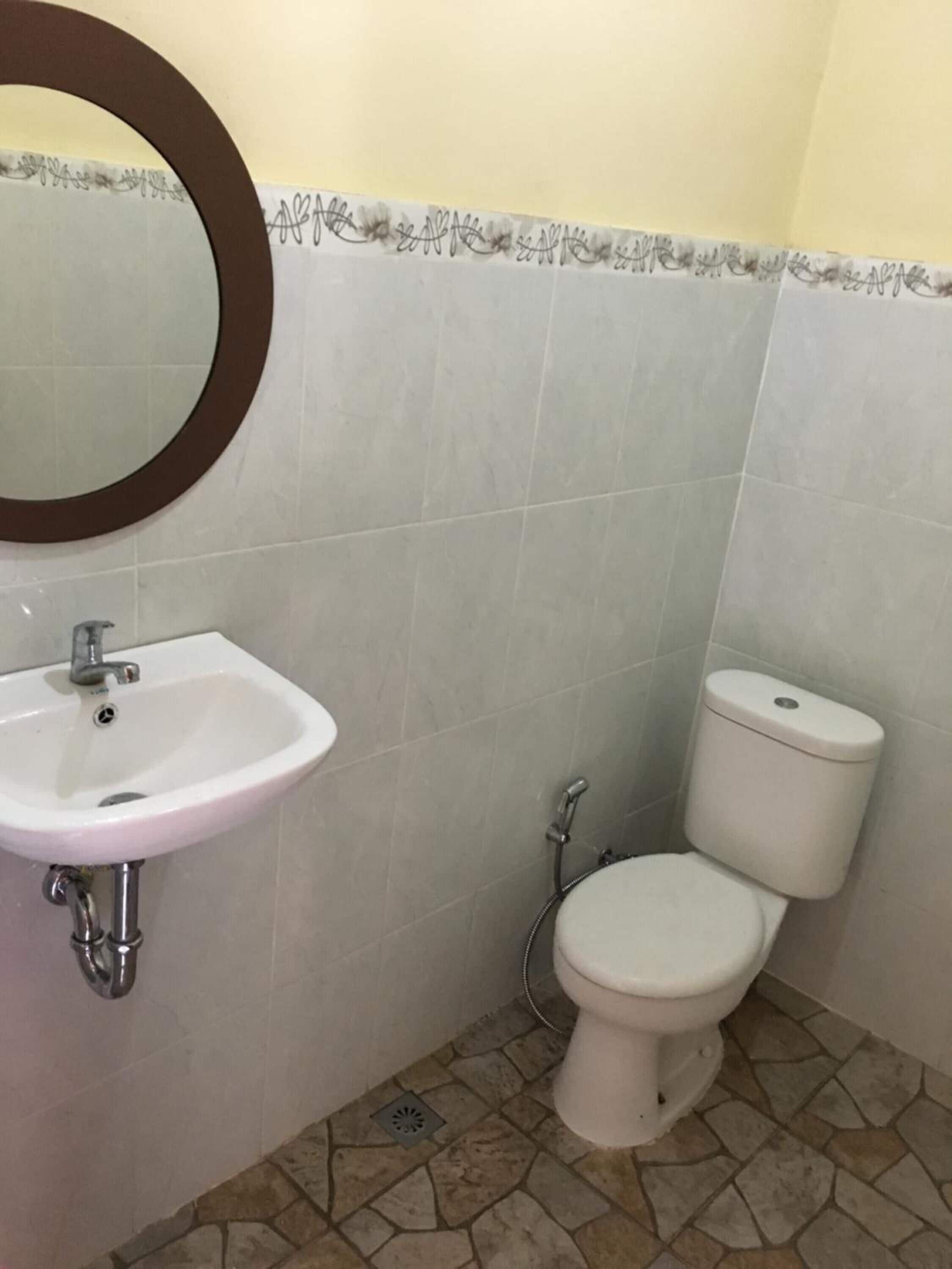 Une salle de bain avec un lavabo blanc, des toilettes et un miroir doté d’un cadre marron.