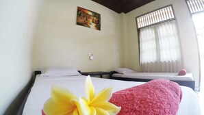 A hotel room with two beds, a painting on the wall, and a window with curtains. - Bali Manik Beach Inn (Kuta)
