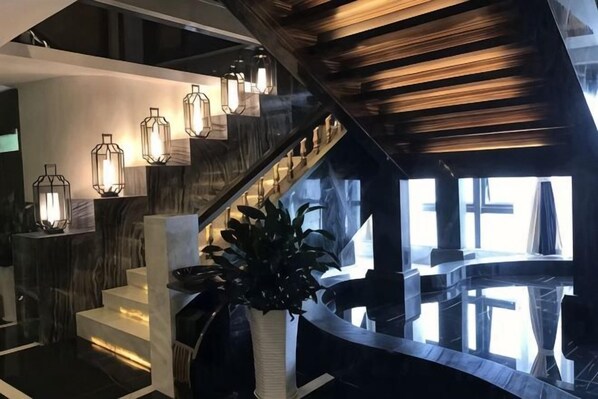 A modern interior with a curved staircase, wooden accents, and pendant lighting.