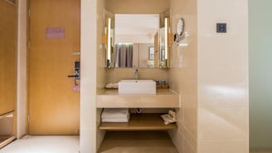 A modern bathroom with a wooden door, a sink, a mirror, and a towel rack.