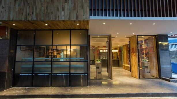 A modern building with a glass facade, wooden paneling, and a well-lit interior.
