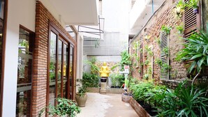 A narrow alleyway with brick walls, potted plants, and a golden statue. - Saravoan Royal Palace (Phnom Penh)