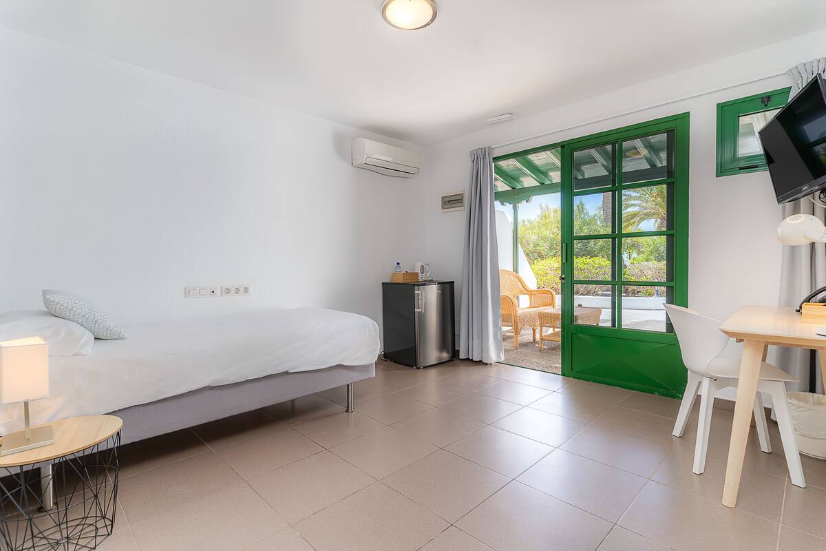 A hotel room with a bed, a desk, a chair, a TV, and a window with a view of the outdoors.