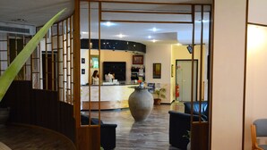 A reception area with a large vase, wooden partitions, and seating. - Castelvetere Hotel (Caulonia)