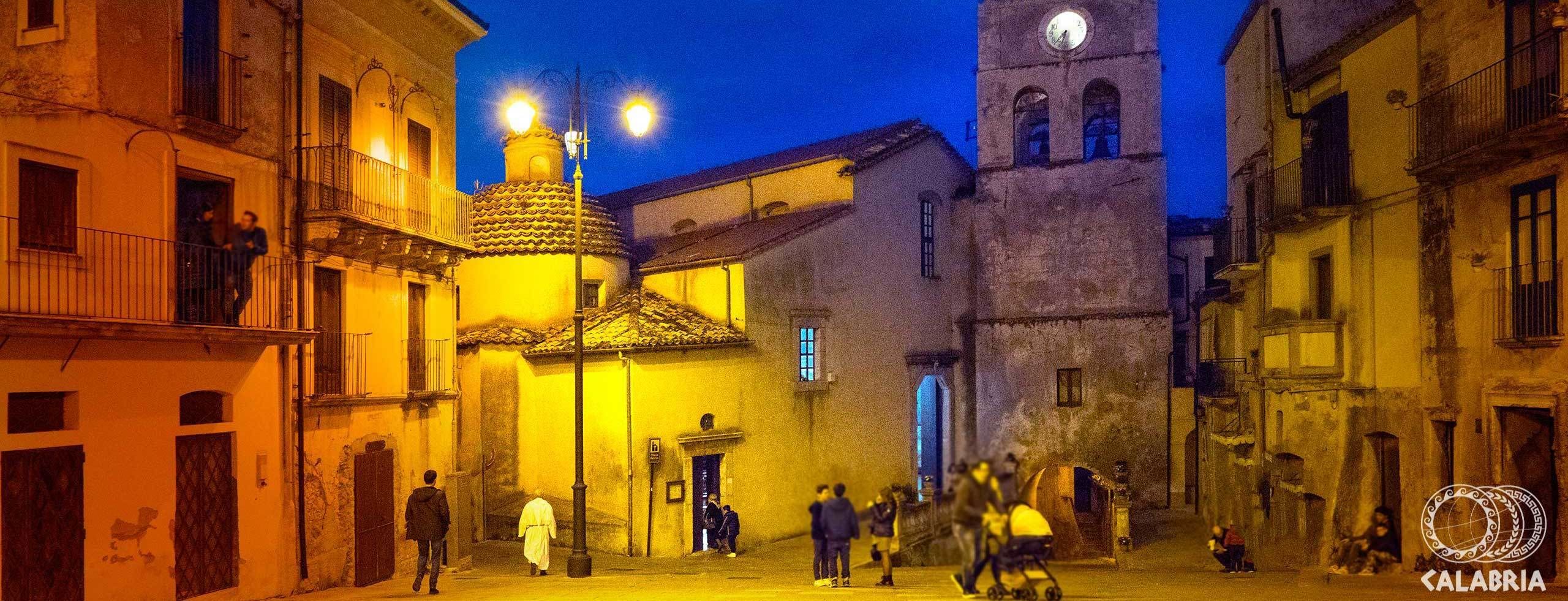 A historic square with a prominent clock tower, traditional architecture, and a few people walking.
