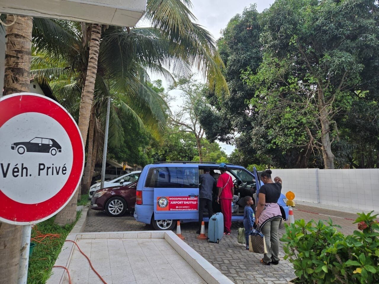 A blue shuttle bus with passengers boarding at a resort.