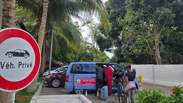 A blue shuttle bus with passengers boarding at a resort.