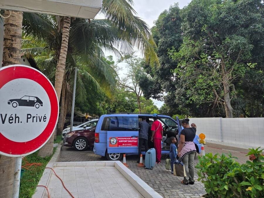 A blue shuttle bus with passengers boarding at a resort.