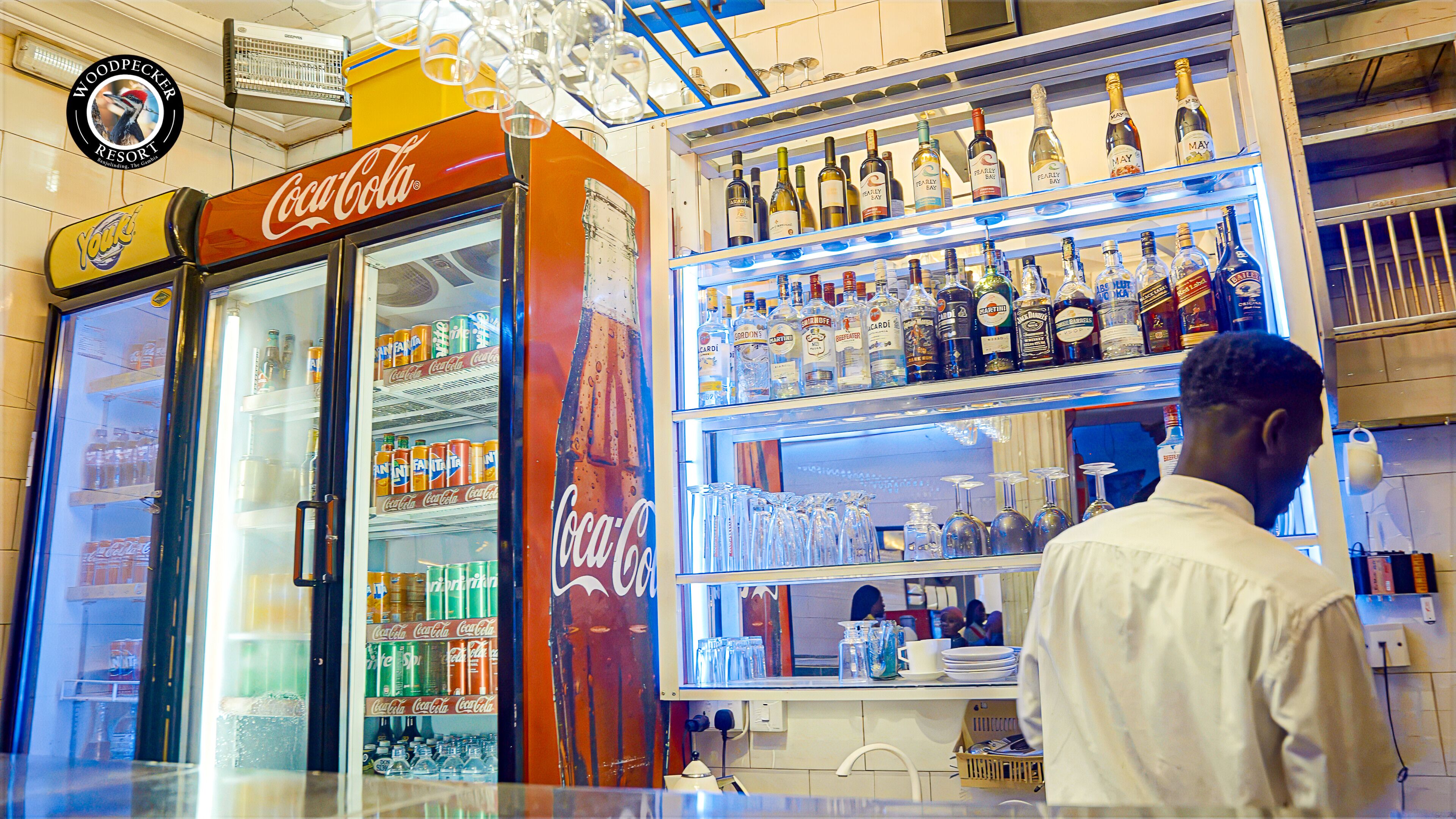 A bar area with a Coca-Cola refrigerator and a liquor display.